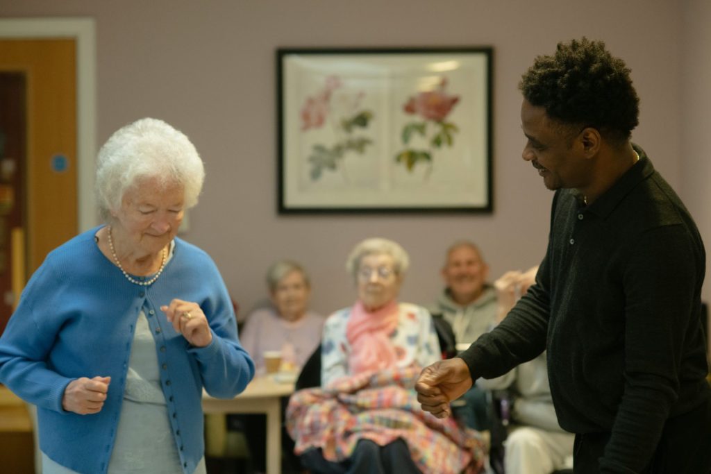 Elderly woman dancing with a man in a room.