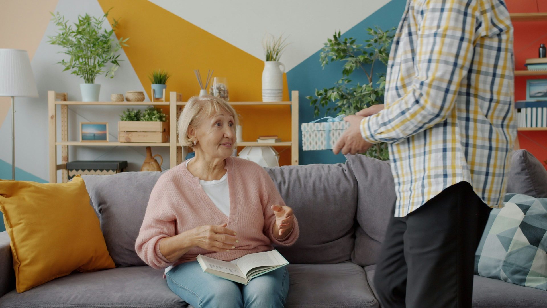 Man gives gift to woman on couch