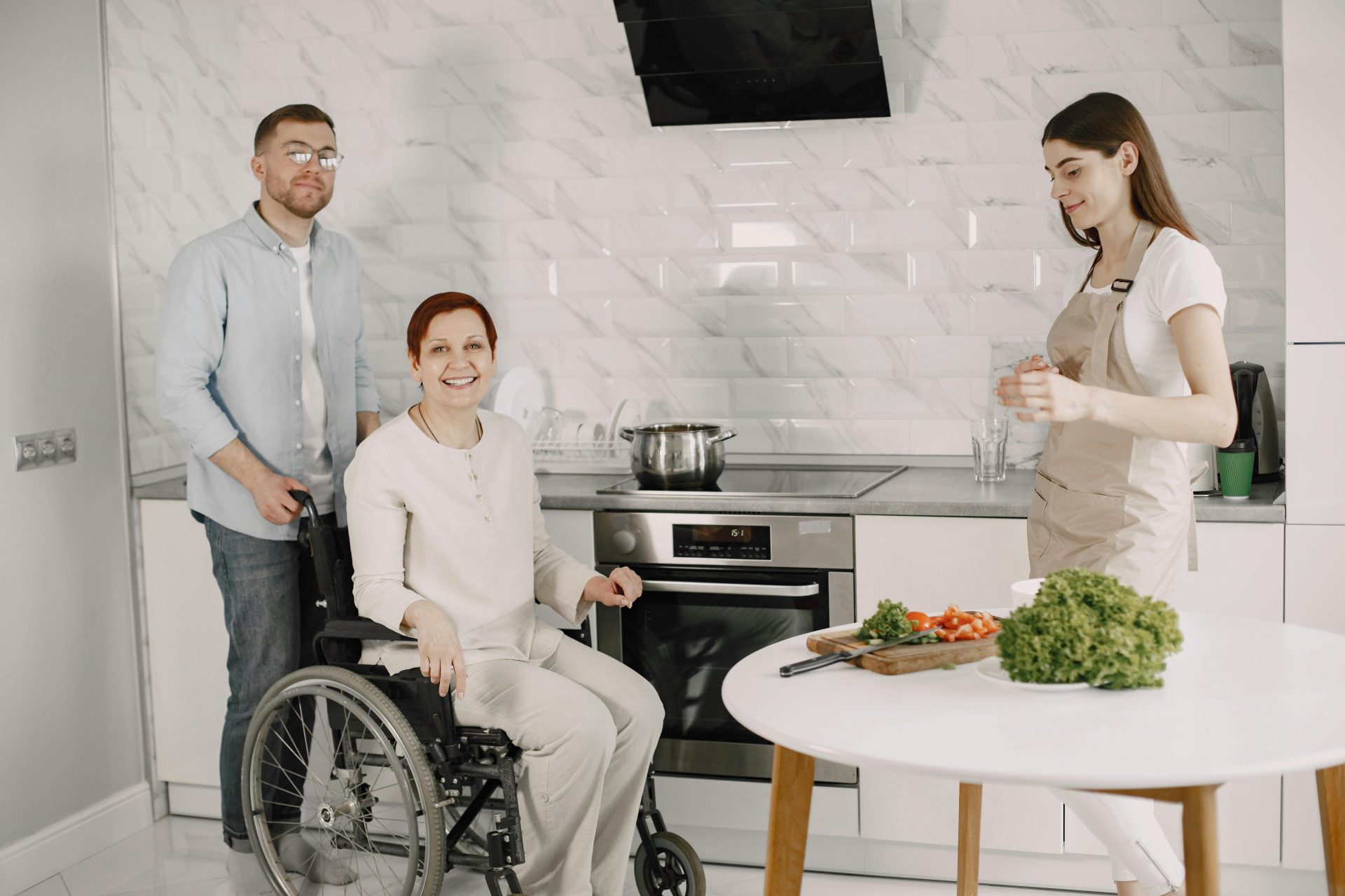 Three adults enjoying family time preparing food in a bright kitchen.